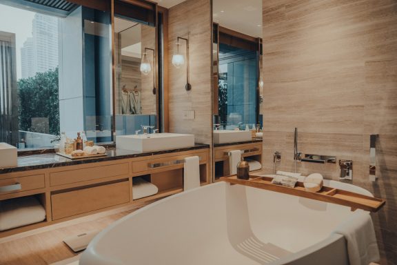 Modern bathroom featuring a freestanding tub, wooden accents, and large mirrors.