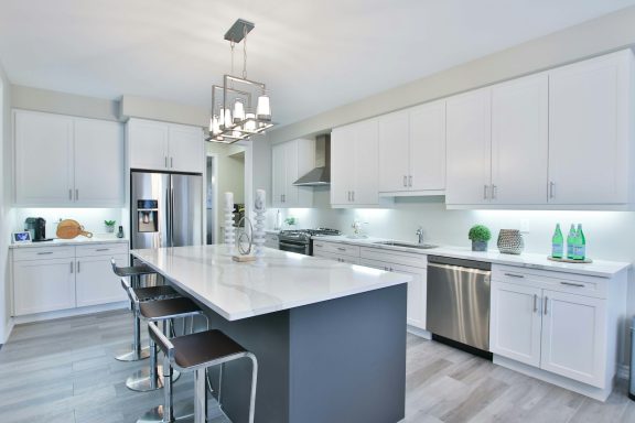 Modern kitchen with a large island, white cabinets, stainless steel appliances, and pendant lighting.