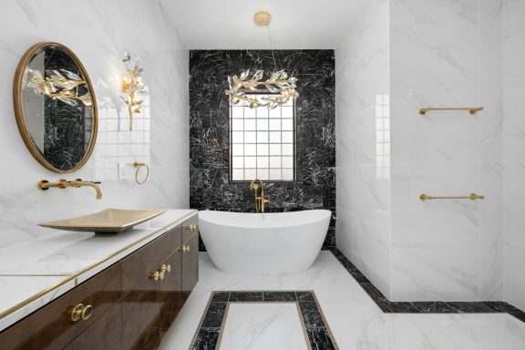 Luxurious bathroom with marble walls, a freestanding tub, and gold fixtures.