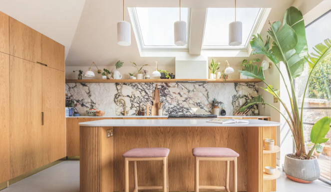 Modern kitchen with wood cabinetry, marble countertops, and large skylights.