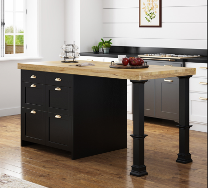 Black kitchen island with wooden countertop and storage drawers, set in a bright room.