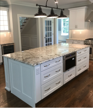 Modern kitchen featuring a marble island with drawers and pendant lighting.